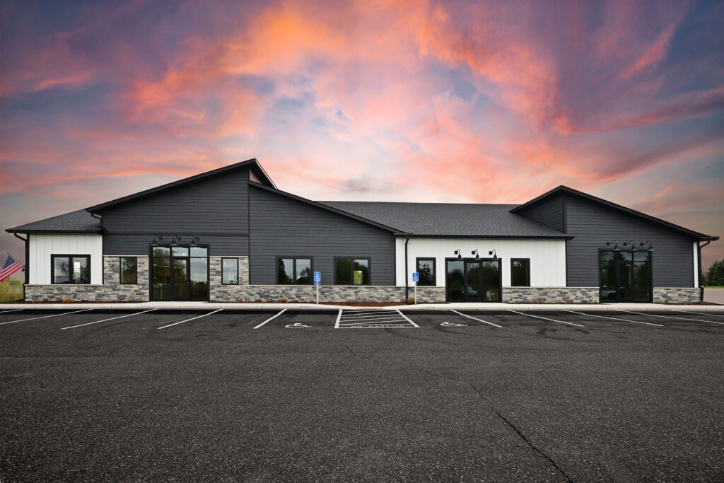 A modern, white and gray professional building under a pink and blue sunset.