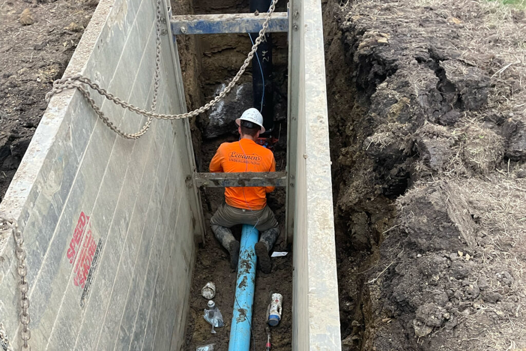 A construction worker works to install underground piping.